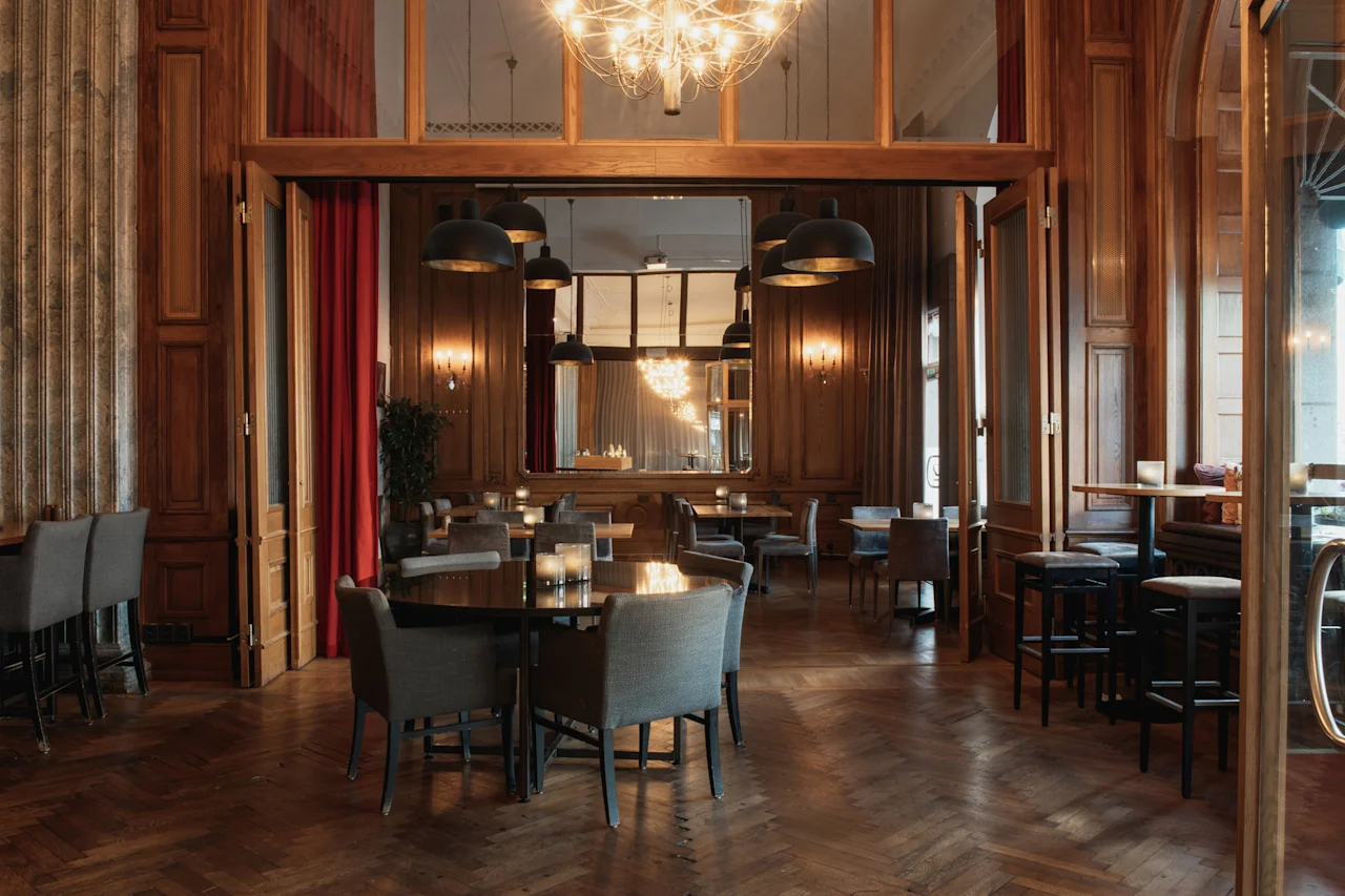 En varm och inbjudande restauranginteriör med trägolv och paneler, redo för middag. Home Hotel Grand, Helsingborg.