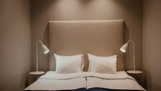 Et hyggeligt hotelværelse på Home Hotel Wellington med en redt seng, blød belysning og sengelamper, klar til et afslappende ophold.