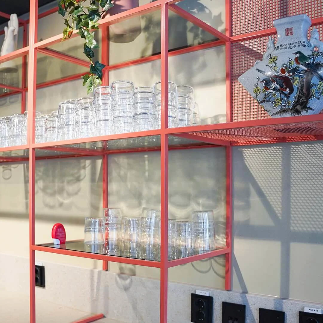 Breakfast area at Comfort Hotel Panorama, red shelves with glassware and a decorative bottle.