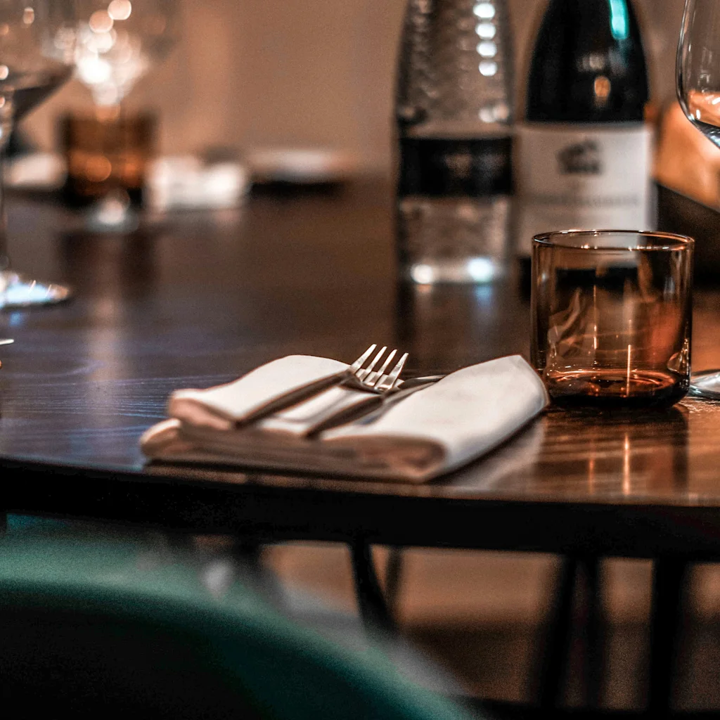 En indbydende restaurantborddækning med gaffel, serviet og drikkevarer, klar til et behageligt måltid.