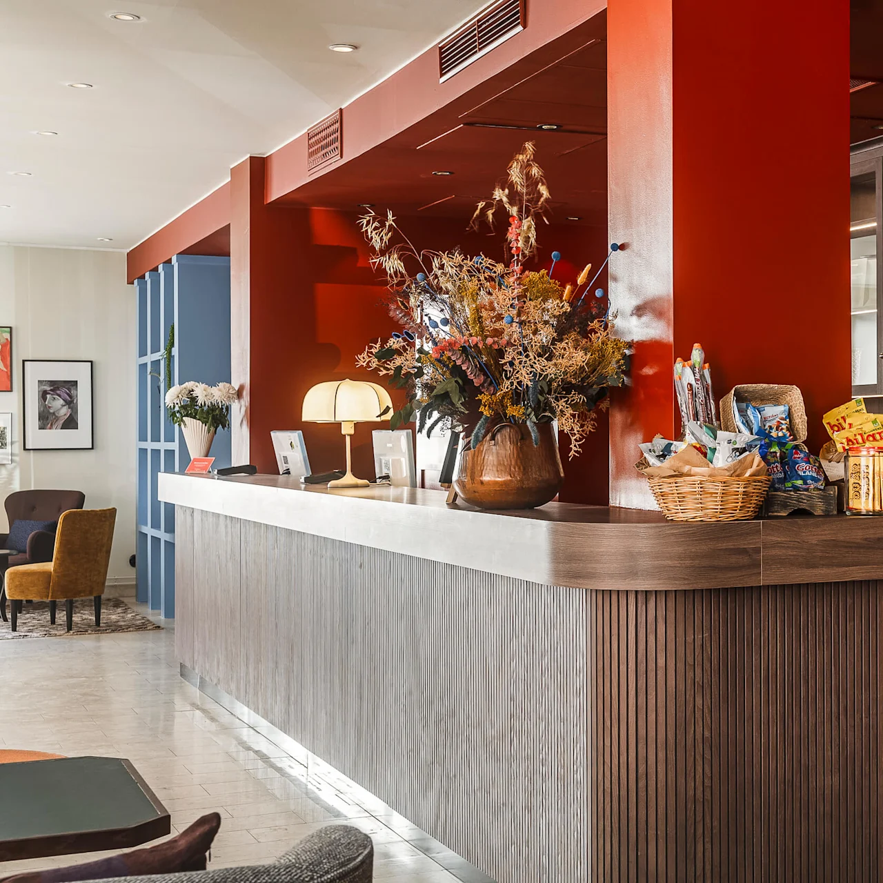 En stilfull hotelllobby med en receptionsdisken, sittplatser och dekorativa växter som skapar en välkomnande atmosfär.
