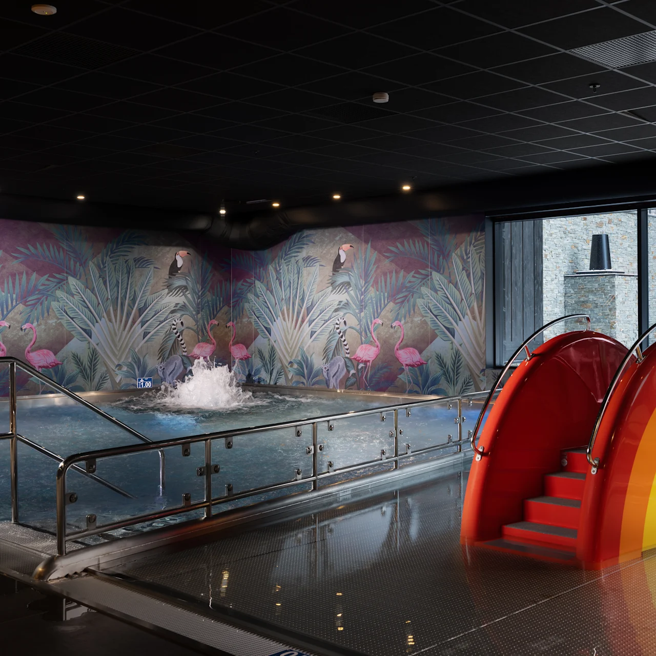 En indendørs pool har en regnbuefarvet rutsjebane, der fører ned i den. Væggene viser tropiske planter med flamingoer, og dæmpet belysning forstærker atmosfæren.