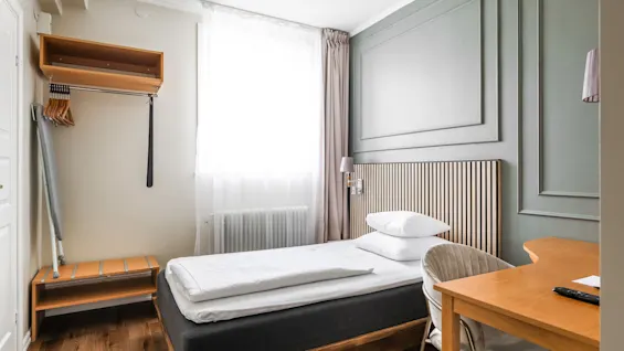 Moderni ja kutsuva hotellihuone Comfort Hotel Linköping Cityssä, jossa on mukava sänky, työpöytä ja vaatekaappi.