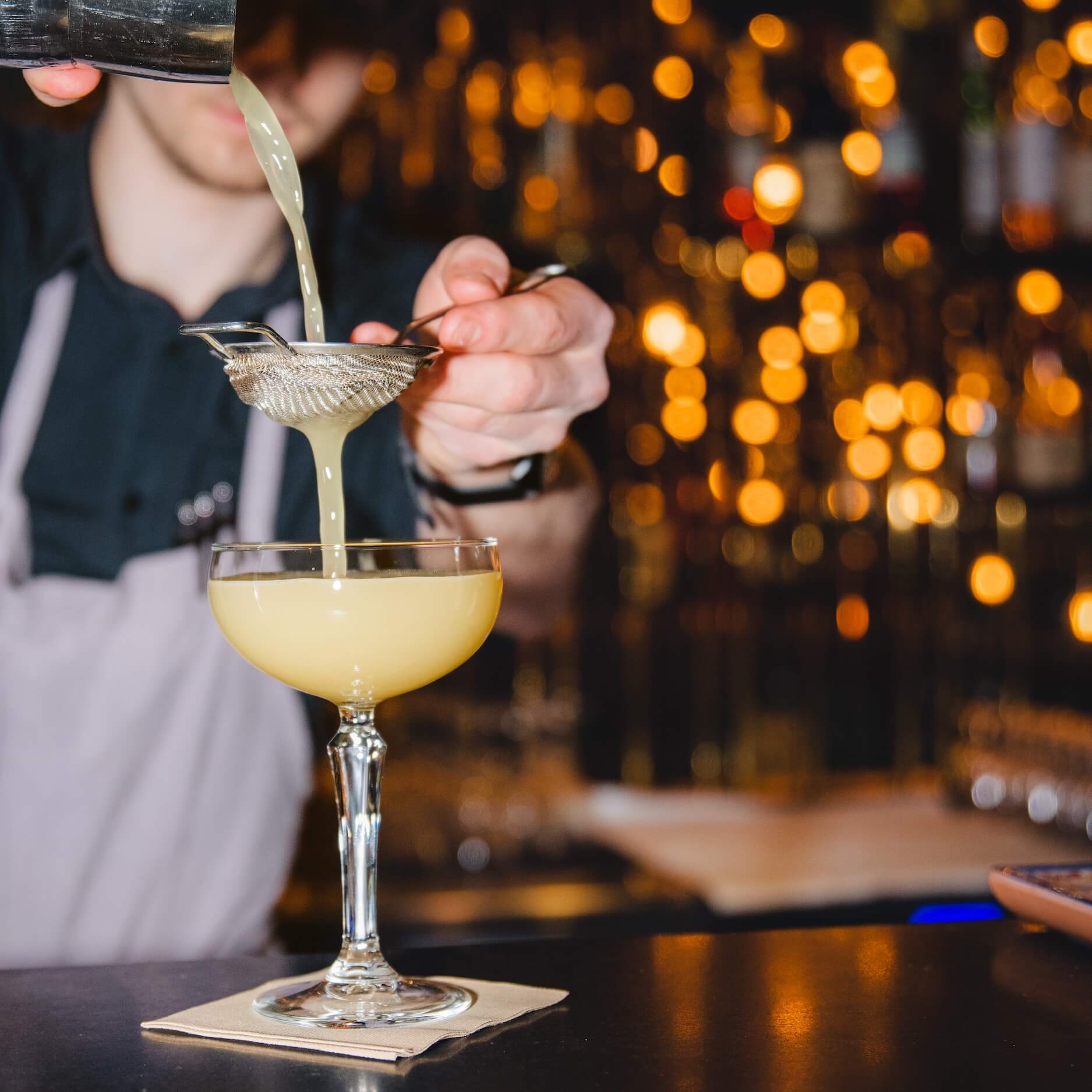 A bartender pouring a yellow drink in a cocktail glas at Kava Cocktail.