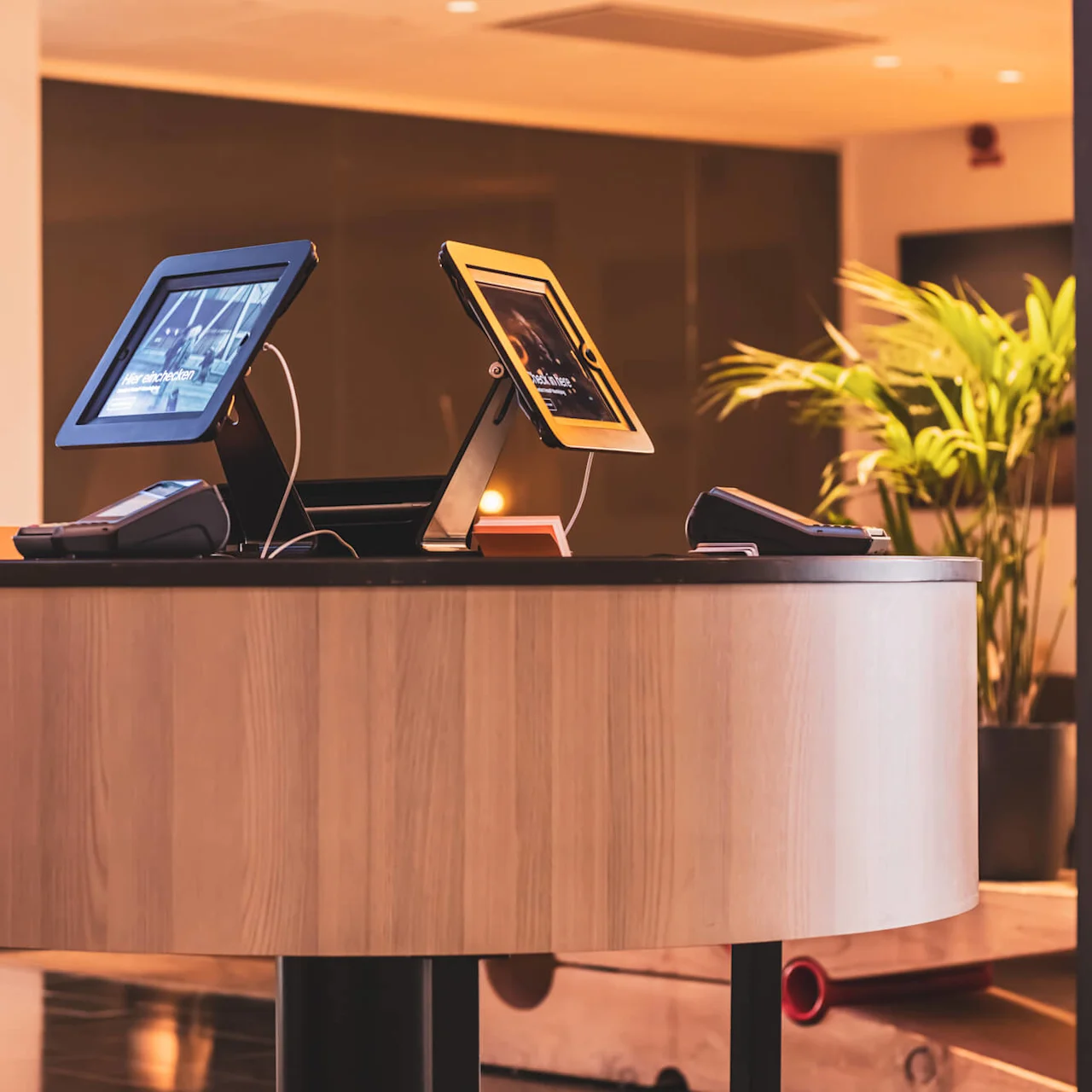 To digitale selvbetjeningskiosker på en resepsjonsdisk i en moderne kontorlobby.