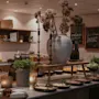 En buffébord visar maträtter och ljus i ett varmt upplyst rum. Menytavlor med texten "Menu," "Glutenfri," och "Vegan" syns på väggarna bakom arrangemanget.