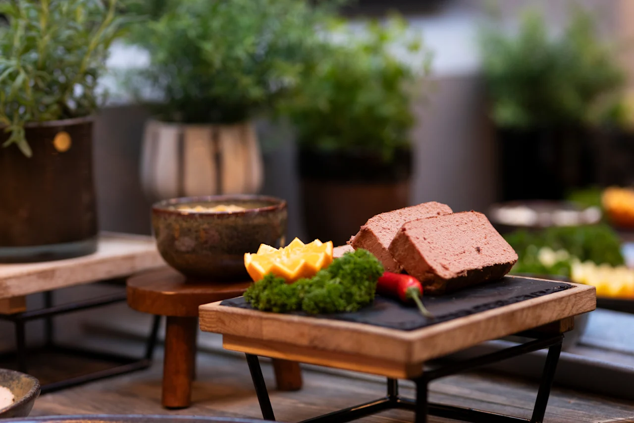 A delicious spread at Home Hotel Grand Bodø, featuring pâté slices garnished with orange, parsley, and chili, alongside a bowl of dip.