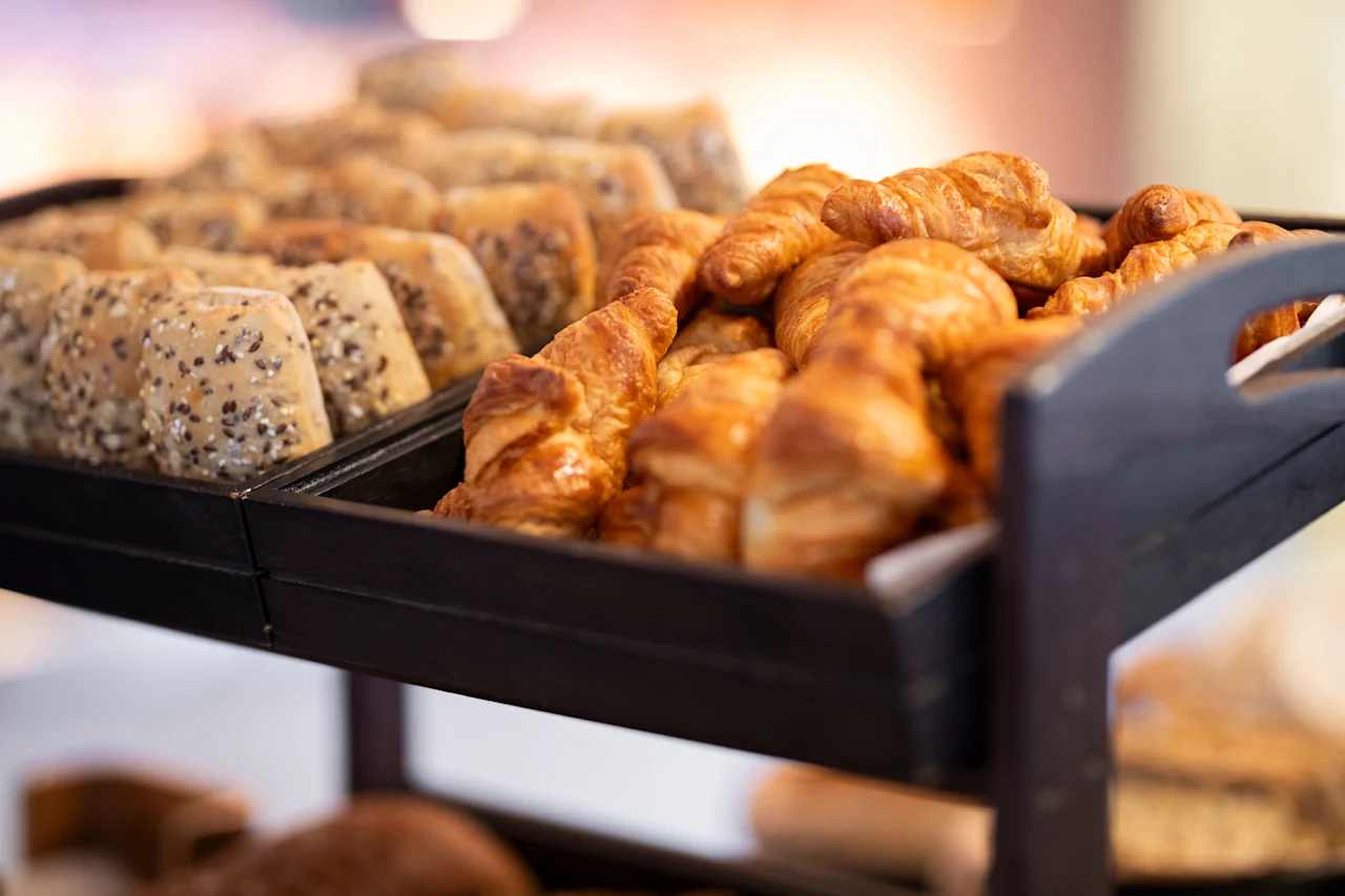 Lähikuva aamiaisbuffetista, jossa on kullanruskeita croissanteja ja siemenleipiä.