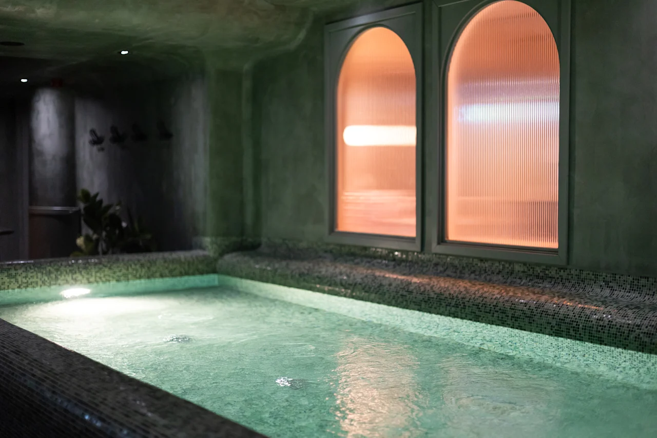 Rauhallinen sisäuima-allasalue porealtaalla ja lämpimästi hehkuvilla kaarevilla ikkunoilla, kutsuen rentoutumaan ja rauhoittumaan.