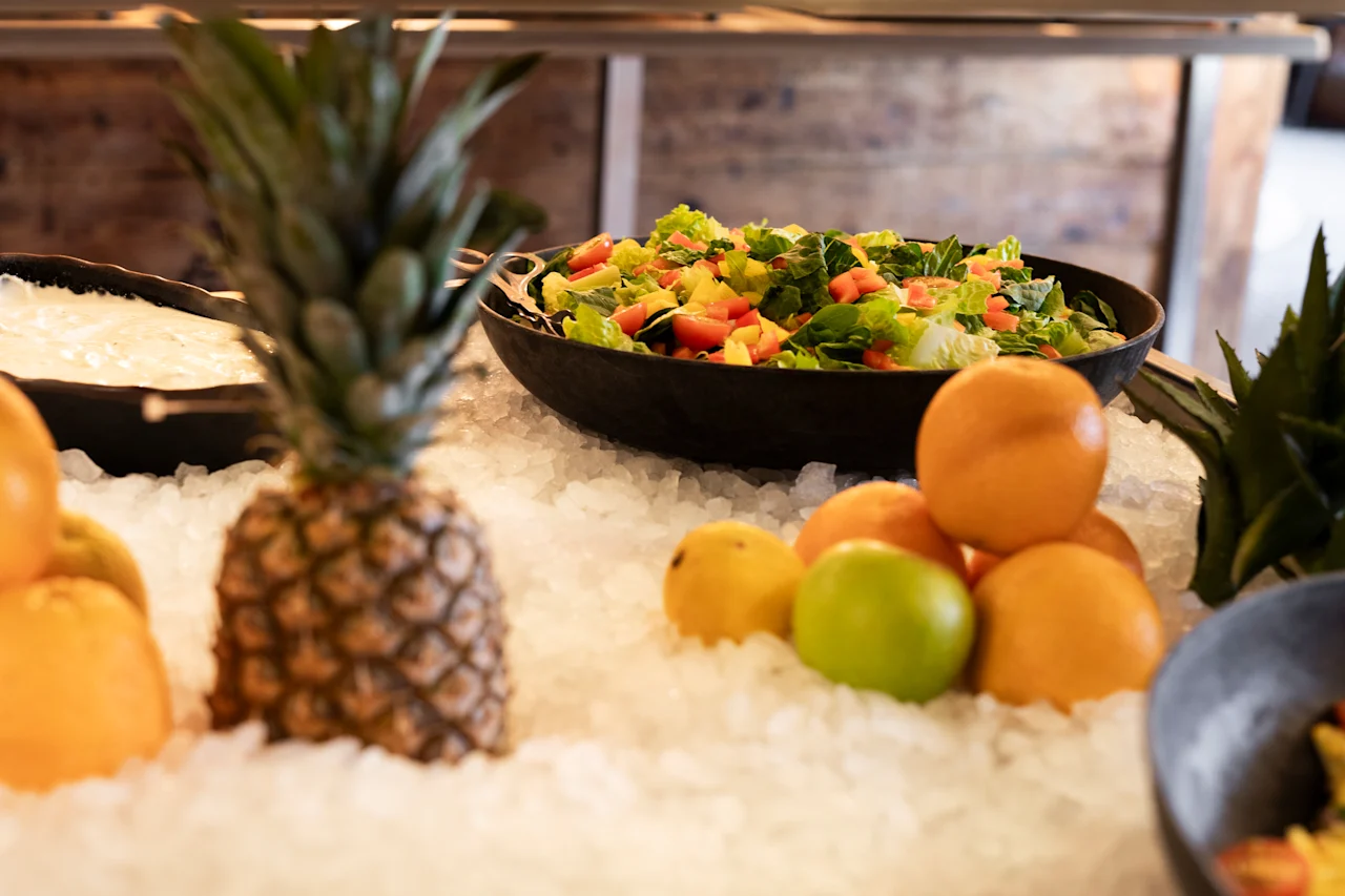 En forfriskende madudstilling med en farverig salat, tropiske frugter og citrus på is, klar til servering.