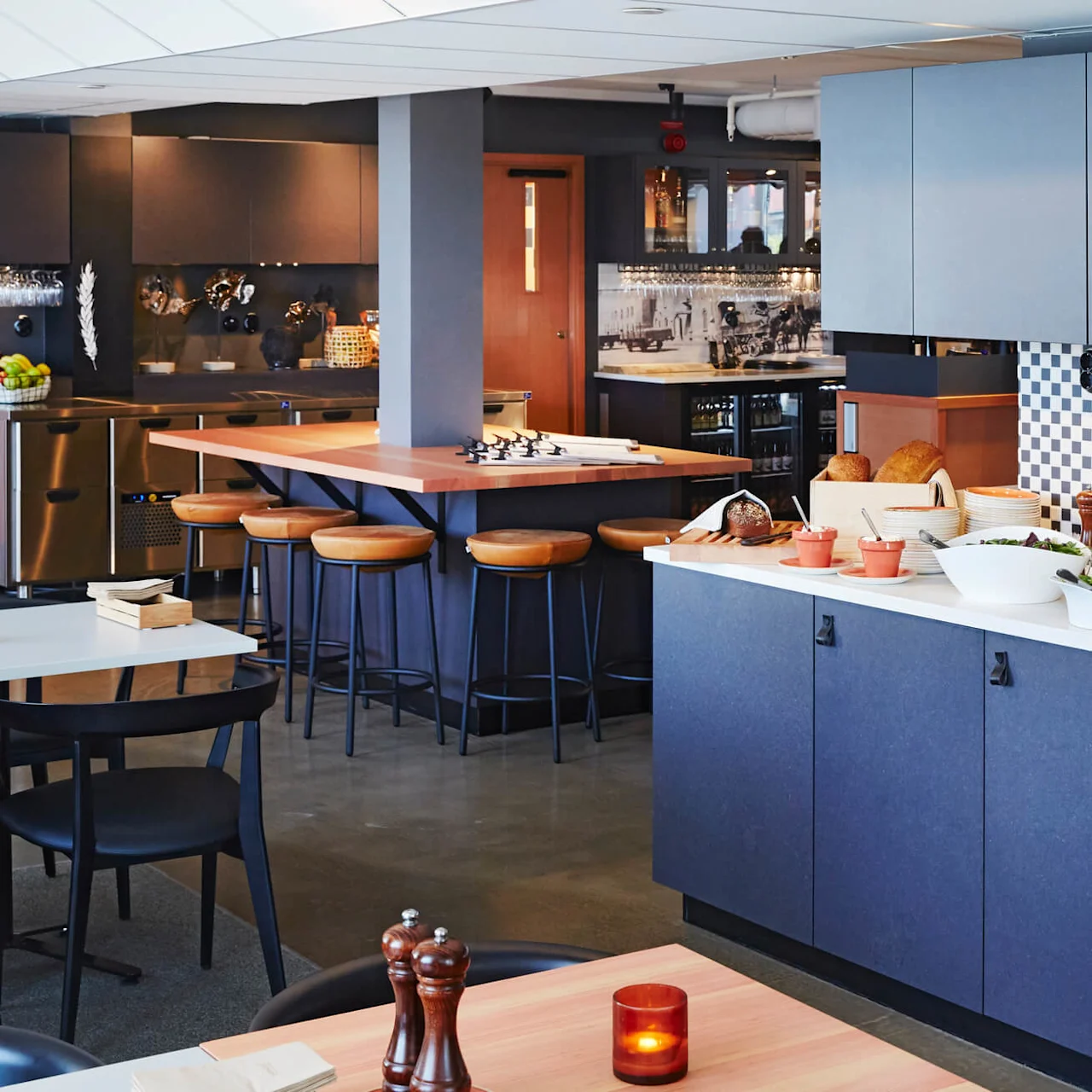 Modern kitchenette with a counter bar, stools, and a buffet spread in a clean, well-lit space.