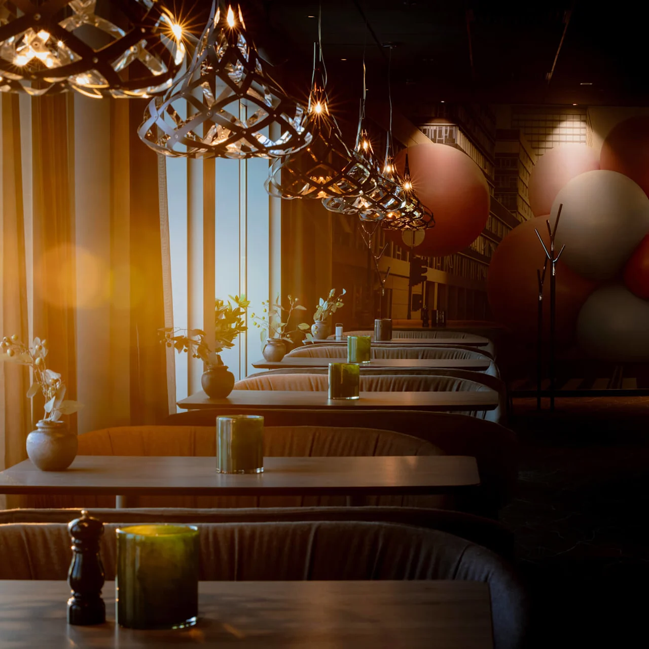 Swedish: Bord med gröna ljus står uppradade under moderna hänglampor, i en svagt upplyst restaurang med en mural av stora överlappande sfärer på väggen.