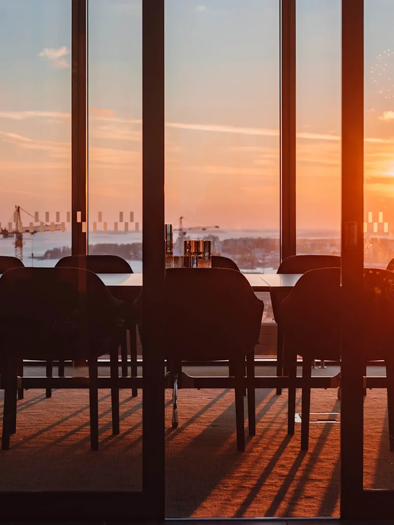 A boardroom with table and chairs on the top floor at sunset at Clarion Hotel® Helsinki in Helsinki.