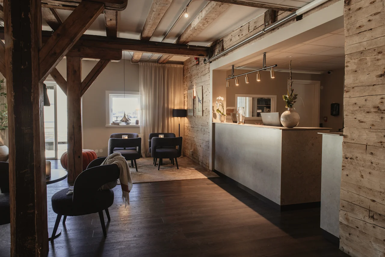 Et stilfuldt og indbydende hotelreceptionsområde med en moderne disk, komfortable siddepladser og rustikke synlige træbjælker.