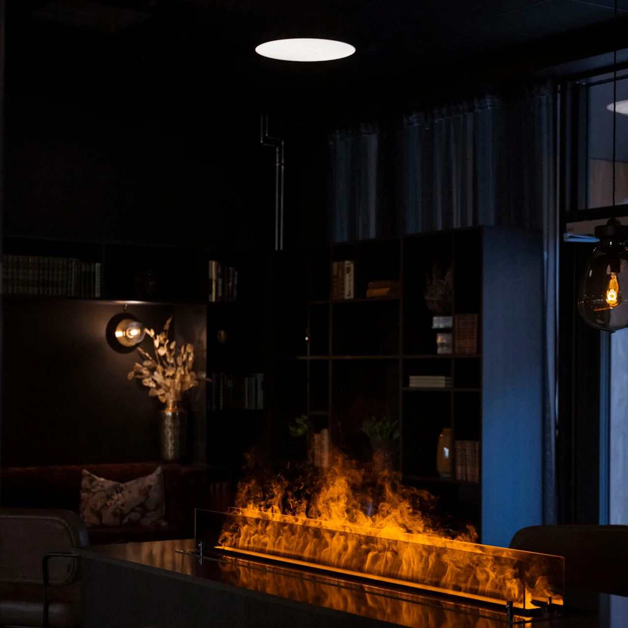 An indoor fireplace glows warmly amid dark, cozy interior decor.