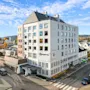 Et lyst hotellbygg i et urbant strøk under en blå himmel med lette skyer
