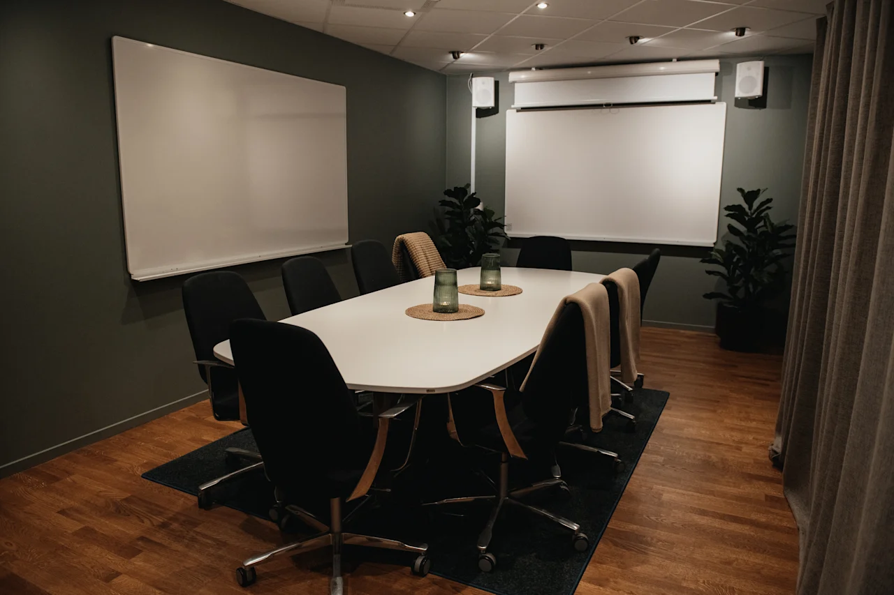 Ett modernt konferensrum med ett långt bord, stolar och presentationsskärmar, redo för produktiva diskussioner.