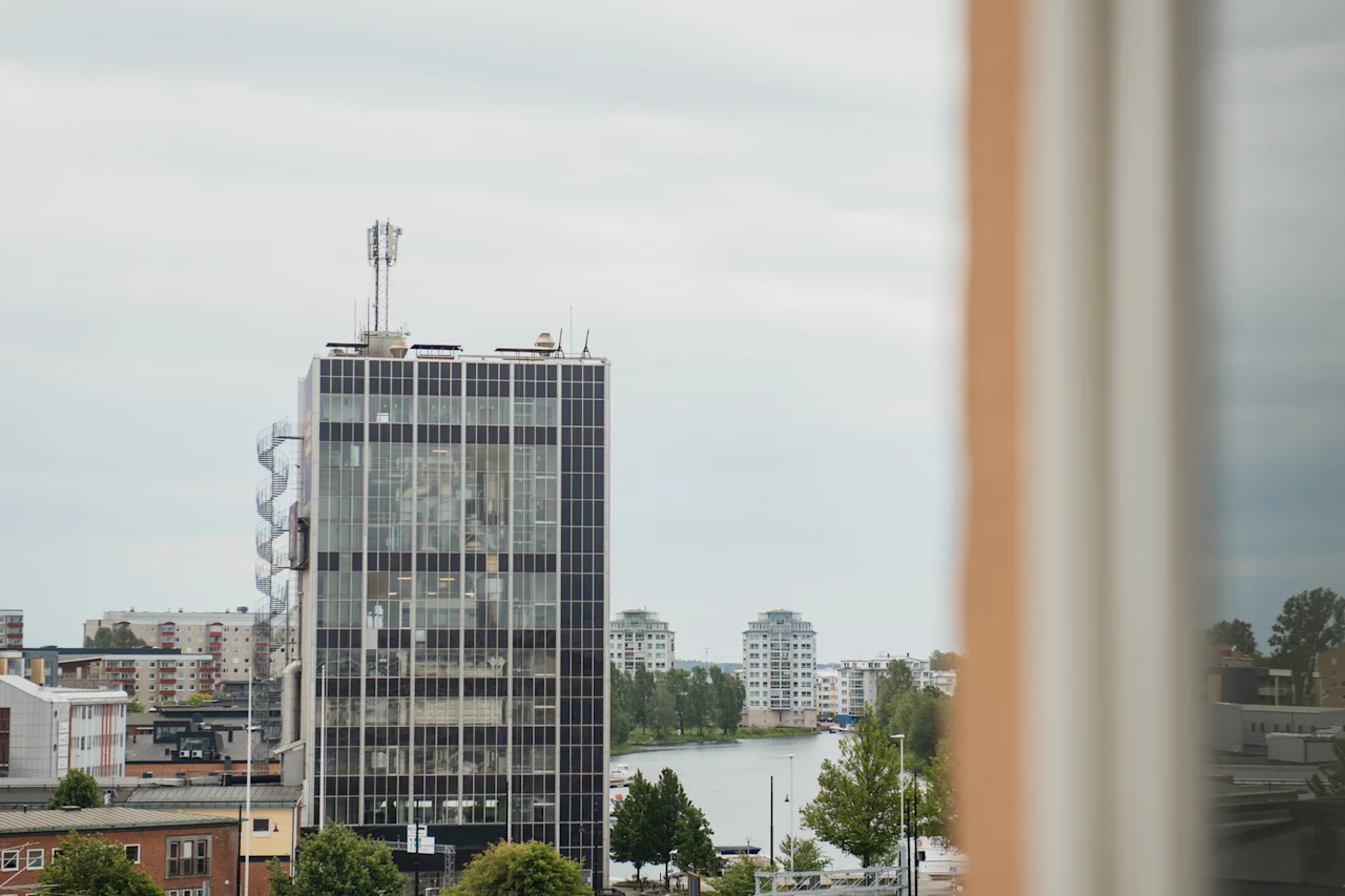 Korkea rakennus, jossa on kierreportaat ja jokinäkymä, nähtynä ikkunasta pilvisenä päivänä.
