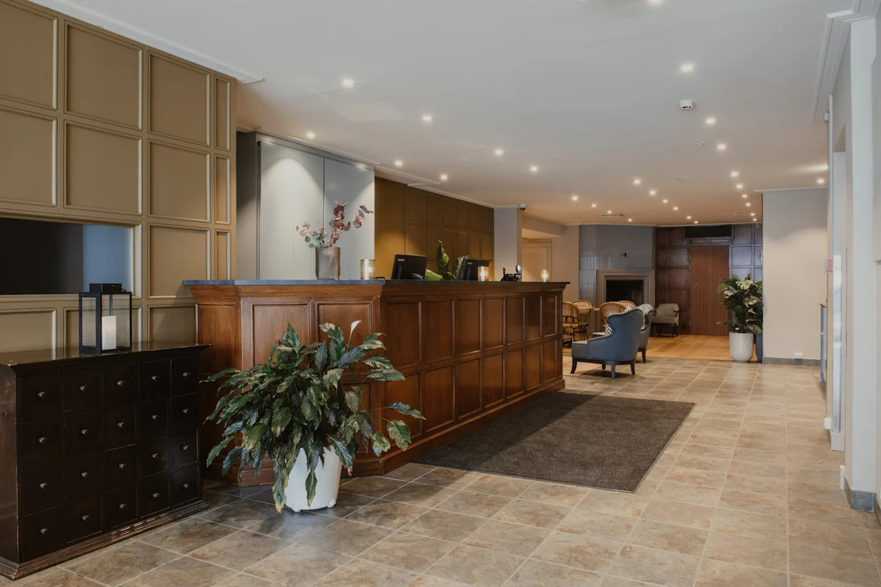 En varm og indbydende hotellobby med en reception i træ, komfortable siddepladser og en hyggelig pejs.