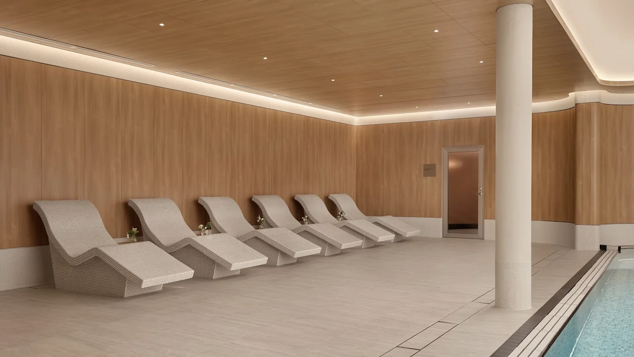 Modern indoor pool area featuring stylish lounge chairs lined up against a light wood wall.