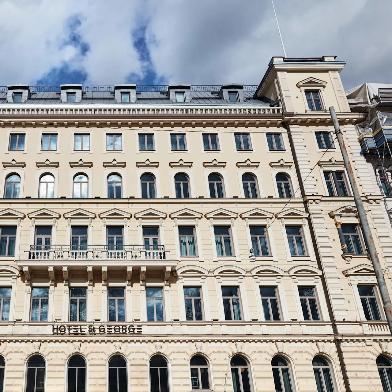 En nyklassicistisk bygningsfacade under en blå himmel med skiltet "HOTEL ST GEORGE."