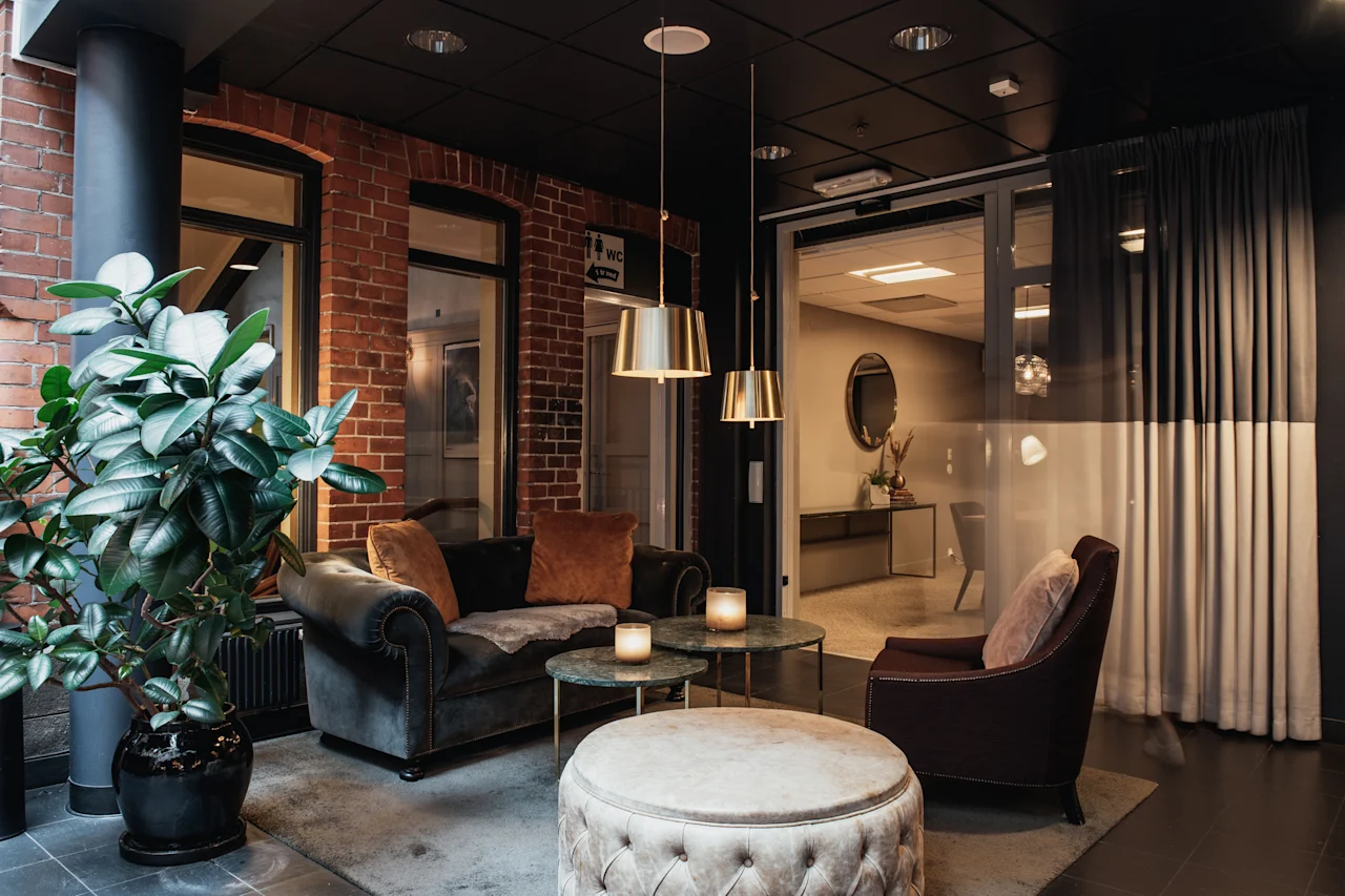 Et stilfuldt og indbydende hotelloungeområde designet til afslapning, med komfortable siddepladser og et WC-skilt.