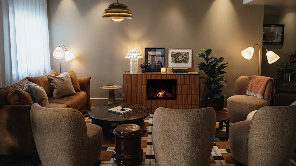 En varm och inbjudande lounge med en tänd öppen spis, bekväma sittplatser och mjuk belysning, perfekt för avkoppling.