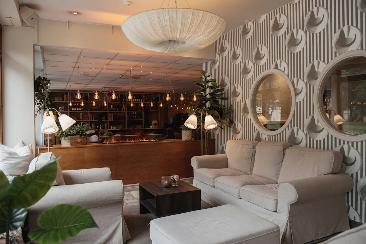A warm and inviting hotel lounge featuring plush seating, ambient lighting, unique decor, and a cozy fireplace for guests to unwind.