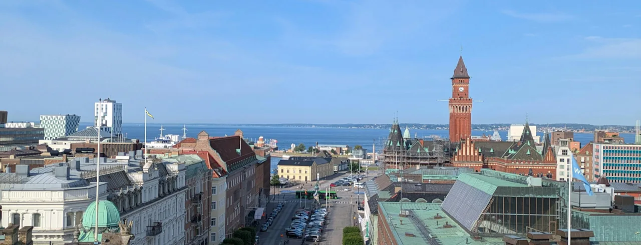 Et fugleperspektiv av en bygata som fører mot vannet, med historiske bygninger og et fremtredende klokketårn.
