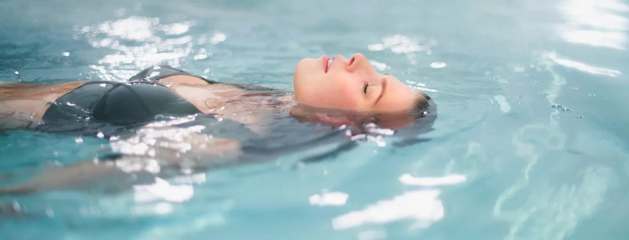 A woman relaxing in a warm and blue pool at Selma Spa in Sunne, Sweden.