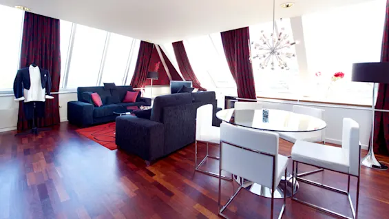 A well-lit lounge room with modern furniture, large windows, and wooden flooring.