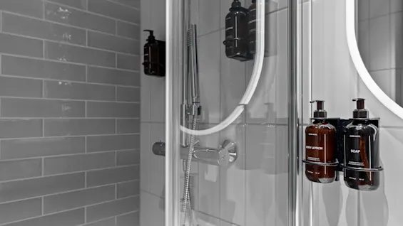 Et moderne bad med dusj og vask, med dispensere for BODY LOTION og HOME HOTEL SOAP. Home Hotel Gabelshus.