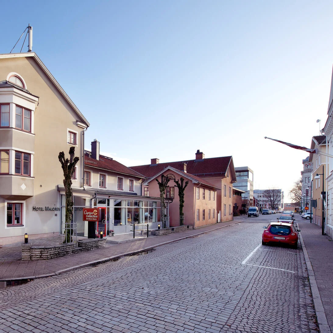 Et gadehjørne med bygninger, ét mærket "HOTEL MADOREN" og "Carino E CaffeBaren."