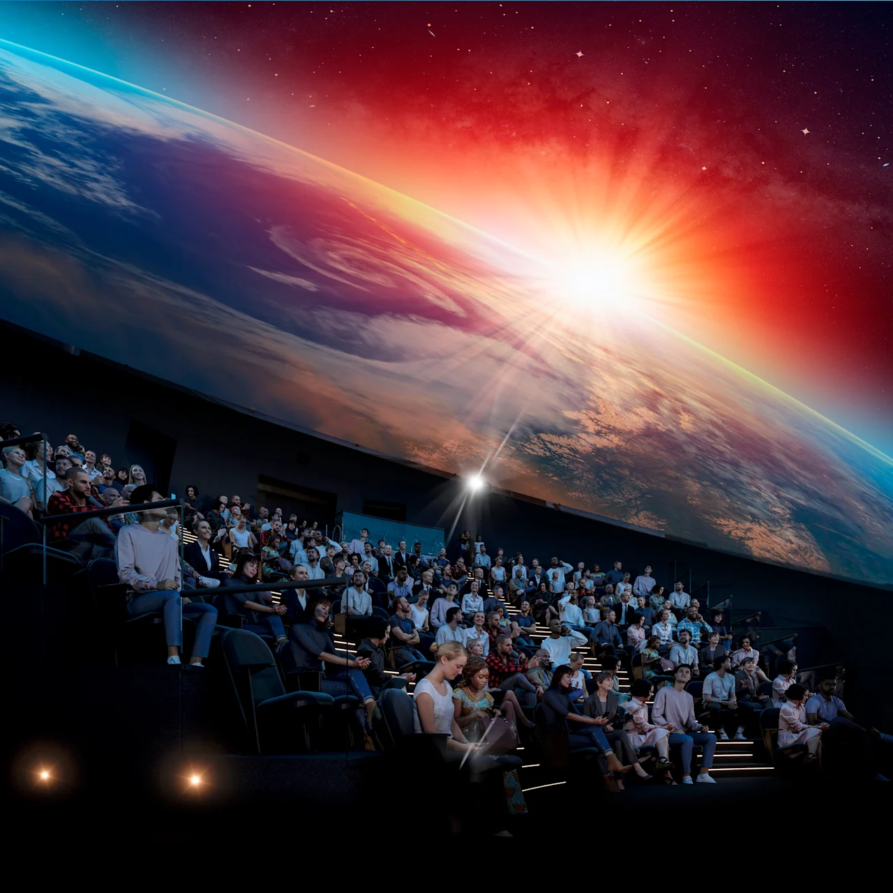 Folk i en mørk teater er fordypet i en fantastisk projeksjon av jorden fra verdensrommet med en strålende soloppgang.