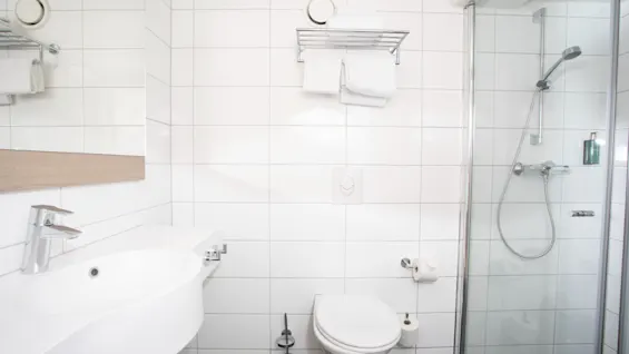 Siisti ja moderni kylpyhuone Home Hotel Bryggeparkenissa, jossa on pesuallas, wc ja suihku, valmiina vieraiden käyttöön.