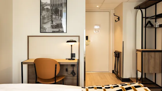 Moderni hotellihuone, jossa on työpiste pöydällä ja tuolilla sekä mukava sänky.
