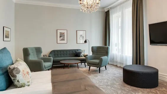 Et pent arrangert stue med moderne møbler og en lysekrone, som reflekterer en koselig og elegant atmosfære.