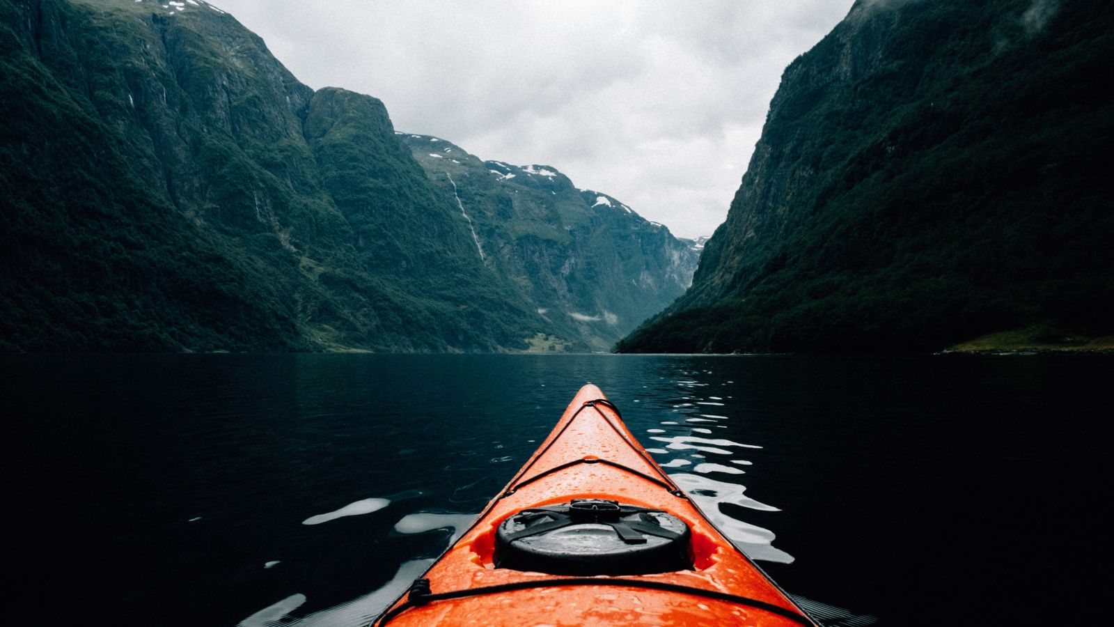 Kayak floating on a fjord between high green mountains