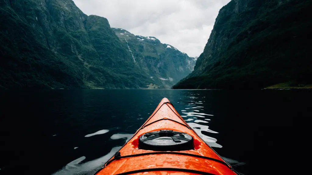 Kayak floating on a fjord between high green mountains