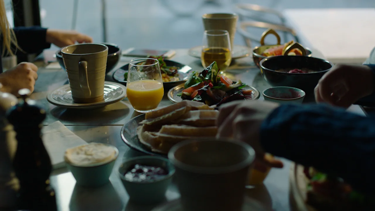 People enjoying breakfast around a table filled with juice, coffee, and bread.