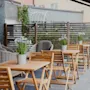 An inviting outdoor patio with wooden tables, chairs, and potted plants, perfect for a relaxing meal or gathering.