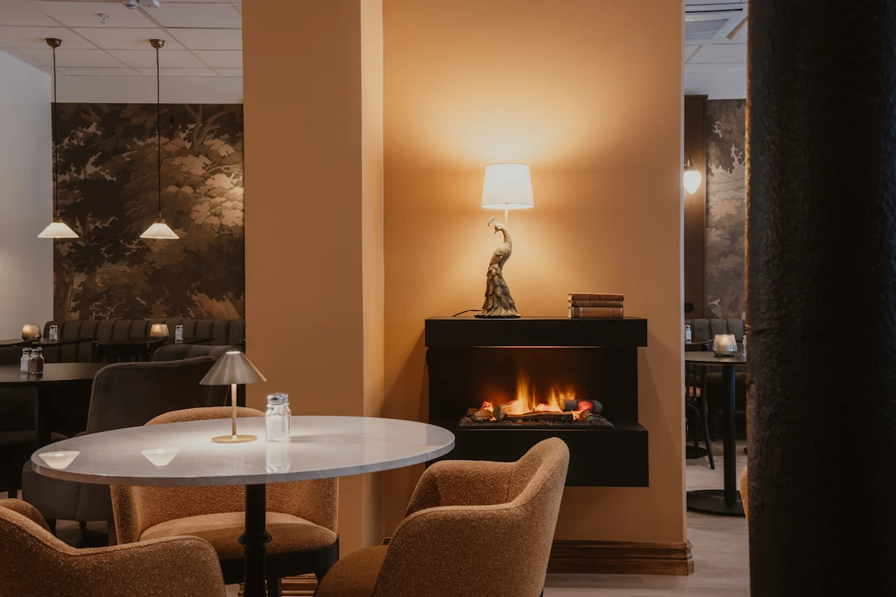 Cozy lounge area at Home Hotel Baltzar with a warm fireplace, comfortable seating, and elegant decor.