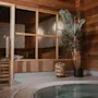 Ett mysigt spaområde med en träbastu med glasdörrar och en bubblande bubbelpool, omgiven av varma träväggar.