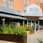 Den innbydende inngangen til Quality Hotel Royal Corner, med frodige grønne planter og et uteserveringsområde under en markise.