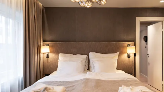 A cozy hotel room at Home Hotel Grand Bodø with a large bed, soft linens, and warm lighting, ready for a relaxing stay.