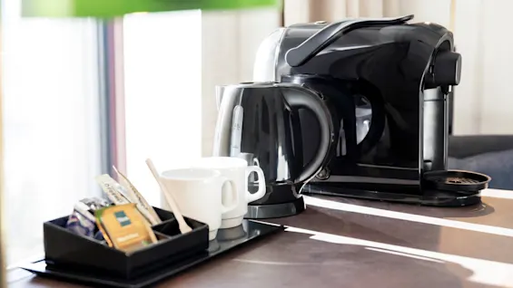 A hotel room coffee and tea station at Quality Hotel The Book, featuring a coffee machine, kettle, mugs, and assorted beverages.