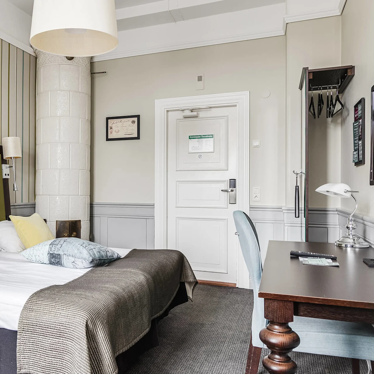 Bed in a neatly organized hotel room with contemporary design, striped wallpaper, and no people.
