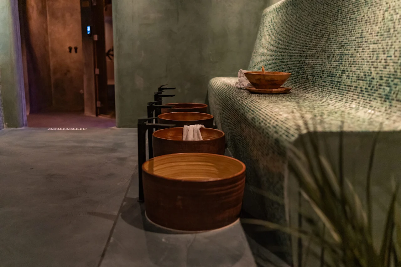 Rauhallinen kylpyläympäristö puisilla jalkakylvyillä ja kaakeloidulla penkillä, valmiina rentoutumiseen.