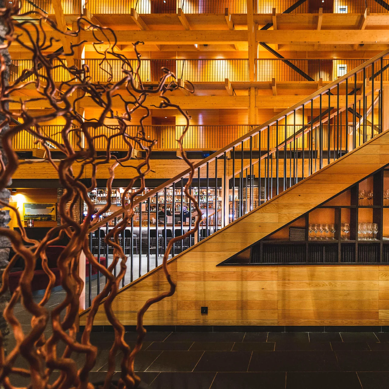 Wood-paneled staircase and wine shelves, warm lighting, modern interior design.