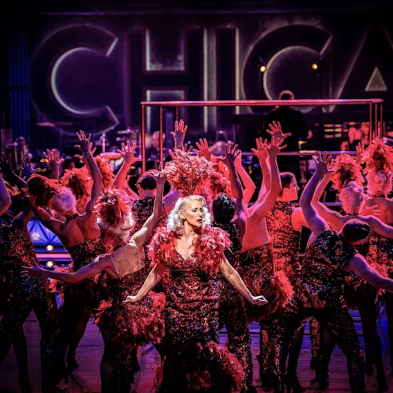 Artister som dansar på scenen under en musikalshow framför en stor Chicago skylt